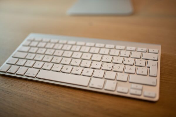 a white keyboard sitting on top of a wooden table