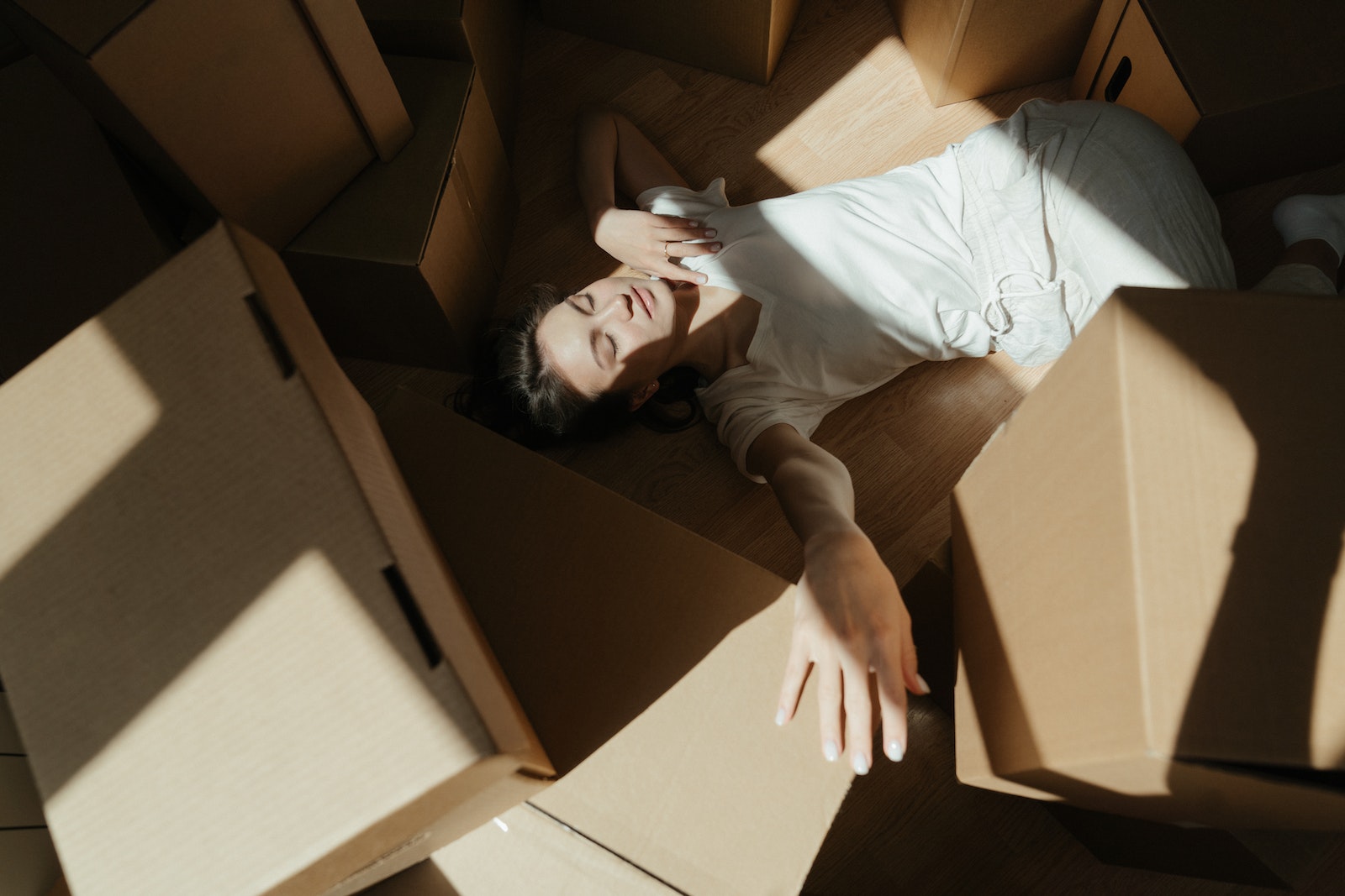 Woman in White Shirt Lying on Brown Cardboard Box